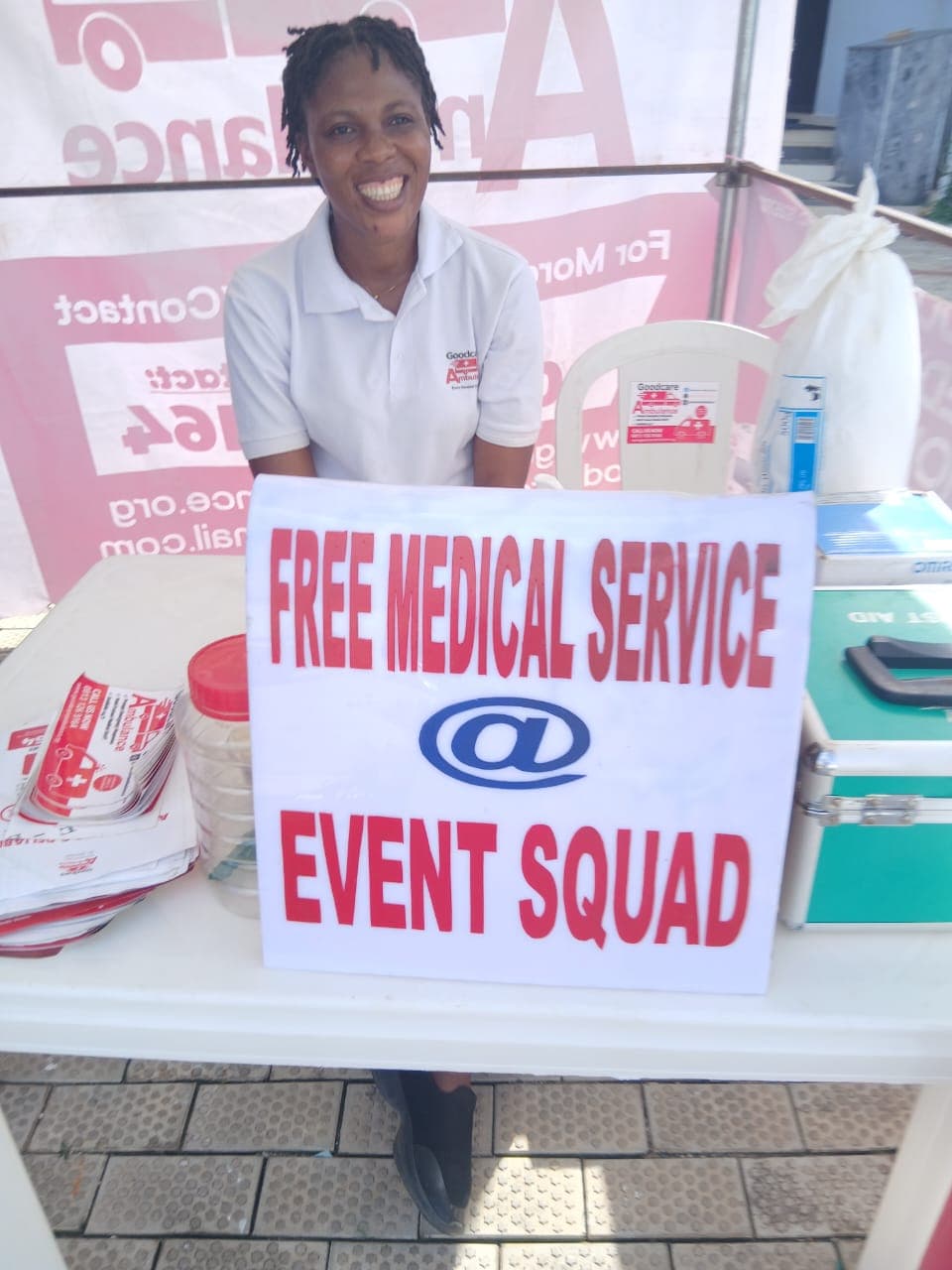 A paramedic at the Event Squad first-aid table beside an ambulance banner and a stocked medical case