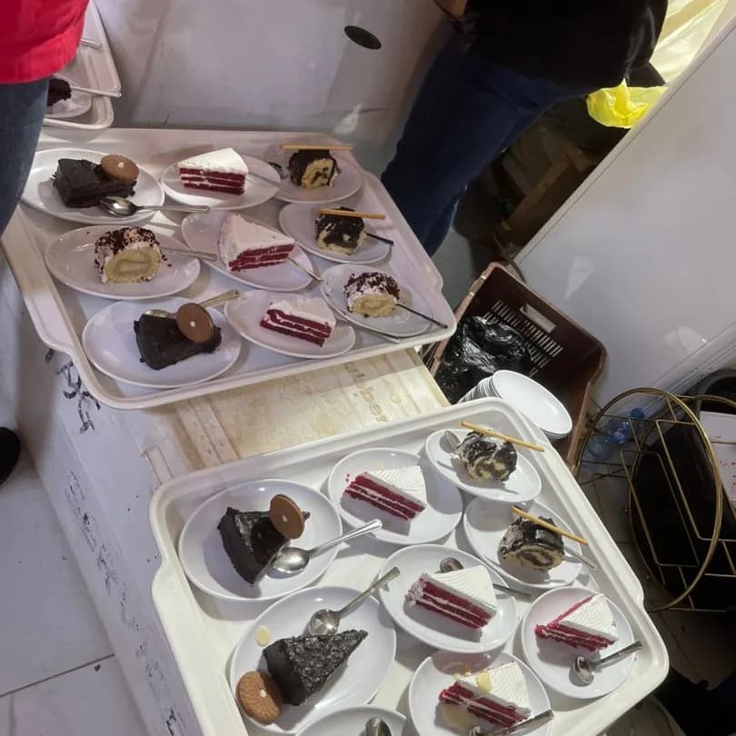 Trays of plated cake — red velvet, chocolate and cream slices — laid out ready for dessert service