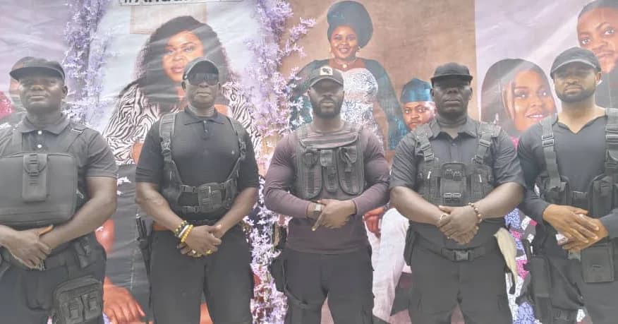 Five Event Squad bouncers in black tactical vests standing across the entrance of a decorated event
