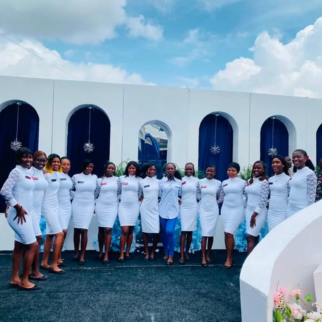 A full usher team in white dresses standing along a white arched backdrop dressed with navy drapes and crystal snowflakes